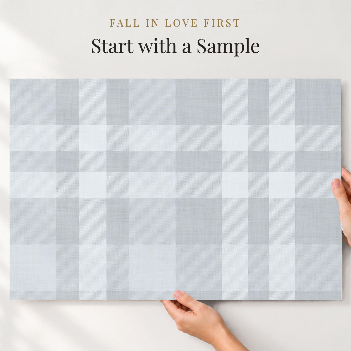 Large sample of dusty blue plaid wallpaper held up to the wall