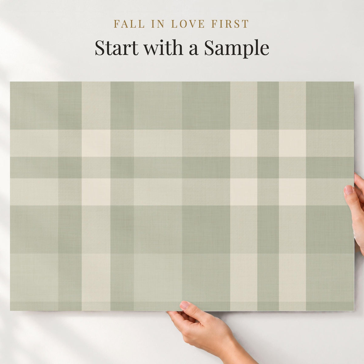 Large sample of sage green plaid wallpaper held up to the wall