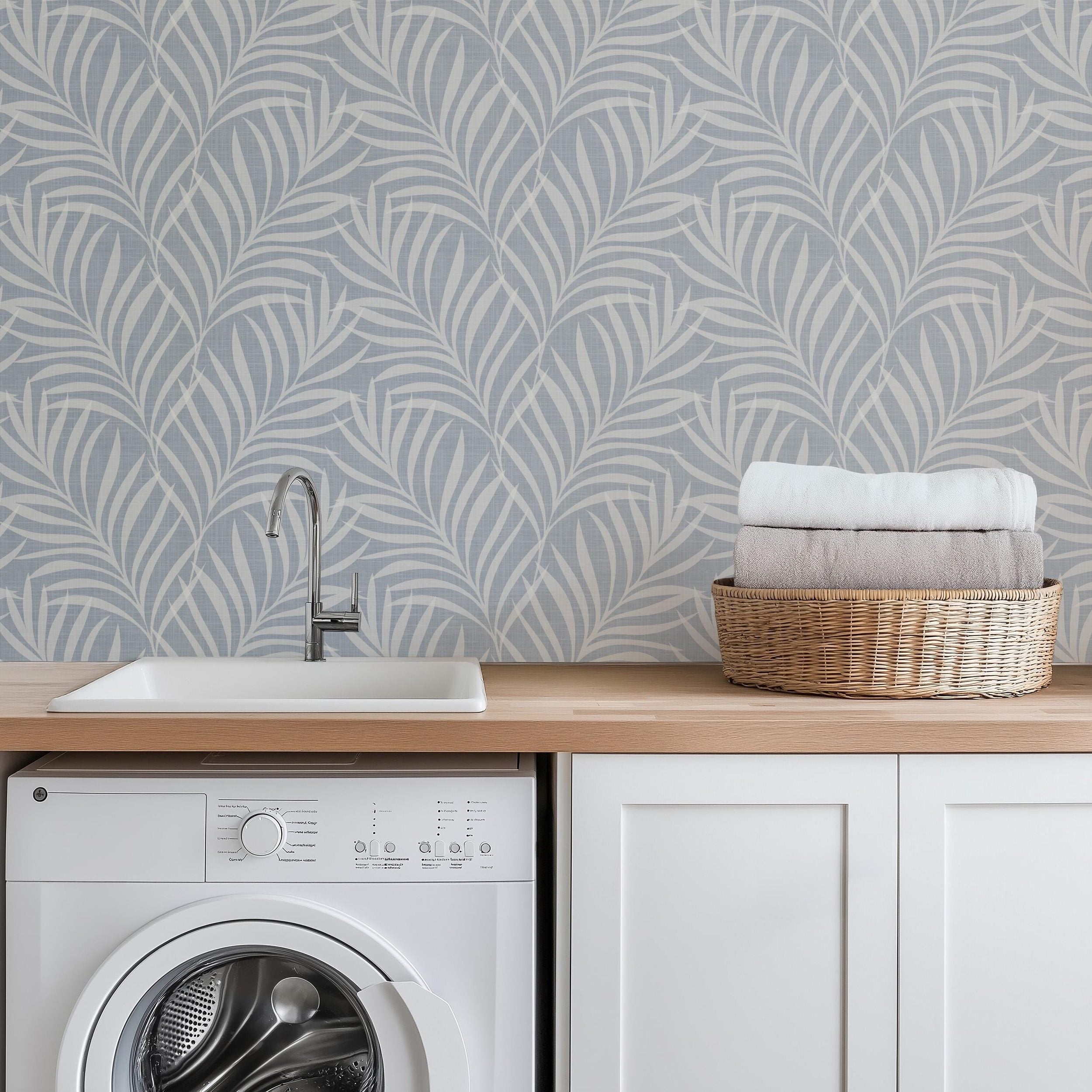 tropical boho palm leaf wallpaper in soft calm blue and white shown in removable peel and stick or prepasted. Perfect for modern coastal bathroom, powder room, nursery or laundry room accent wall.
