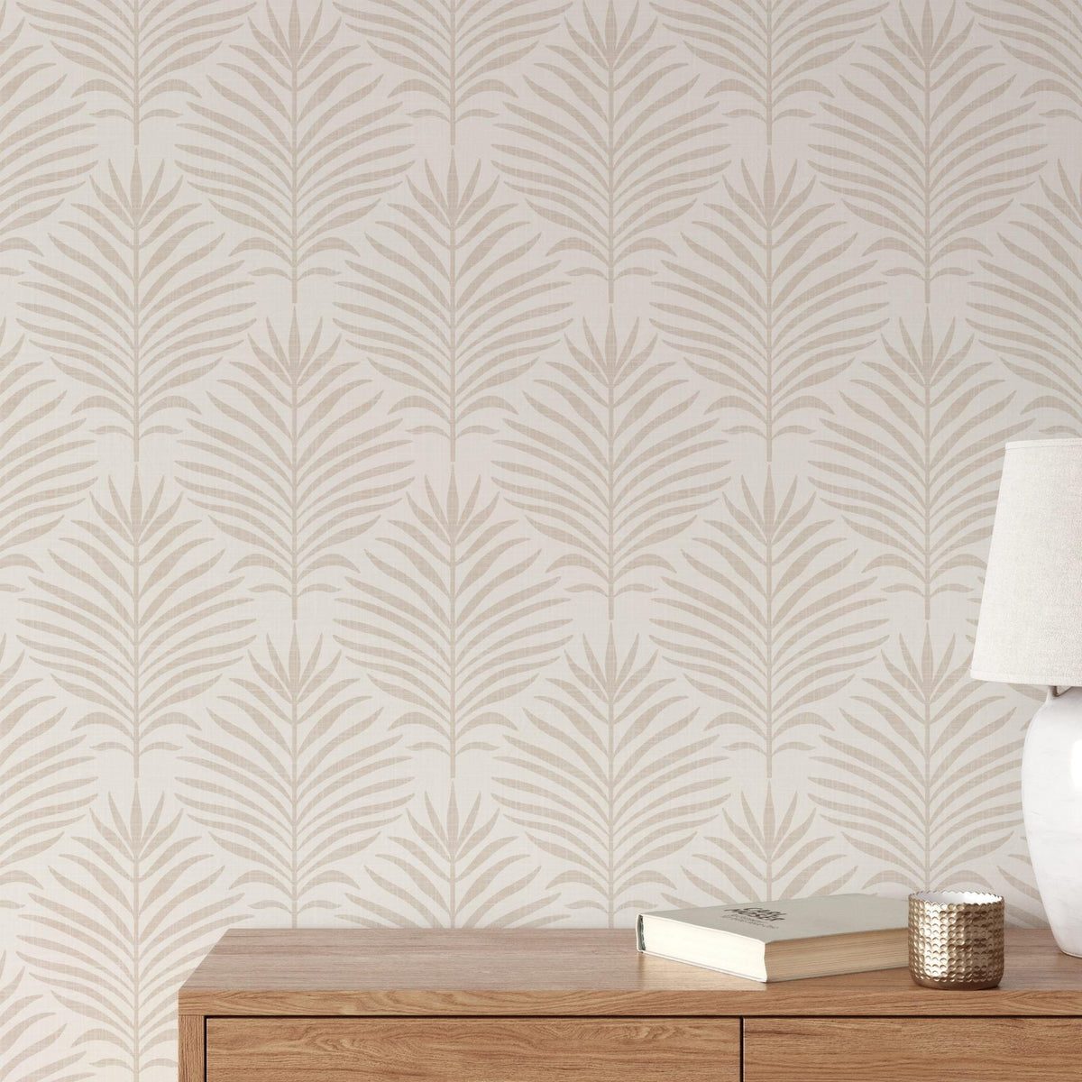 Living room wall of beige and white Palm Breeze palm leaf wallpaper behind a wood sideboard and lamp