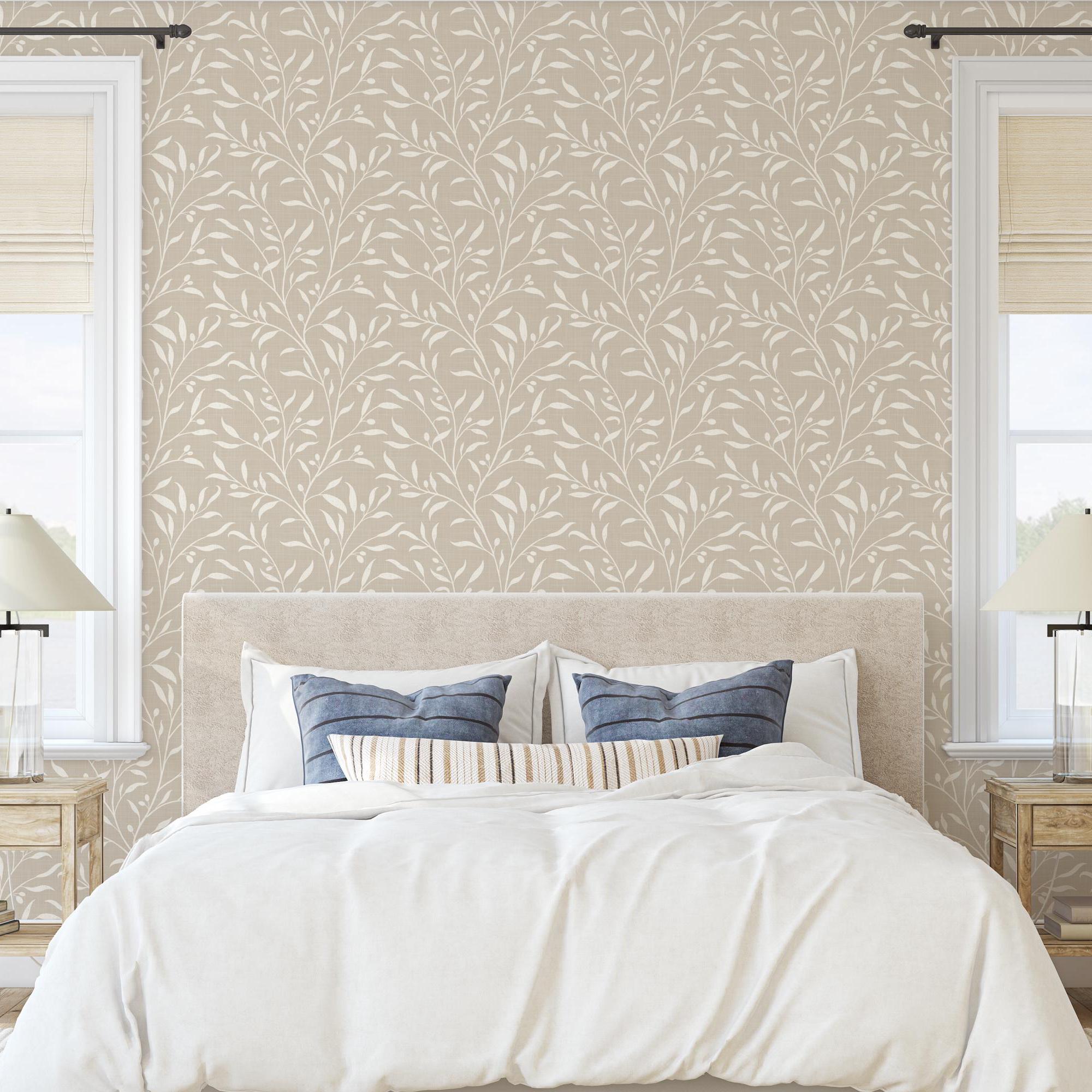 a bedroom with a large bed, white bedding, and a beige wall with a repeating leaf pattern wallpaper. There are two nightstands with lamps on either side of the bed, and a window with white blinds is visible on the right side of the image.