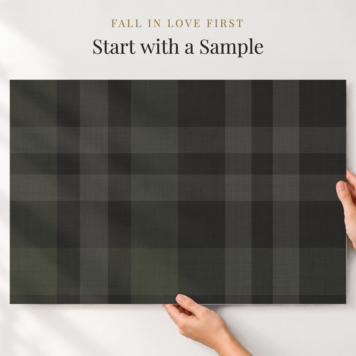 Large sample of charcoal black plaid wallpaper held up to the wall