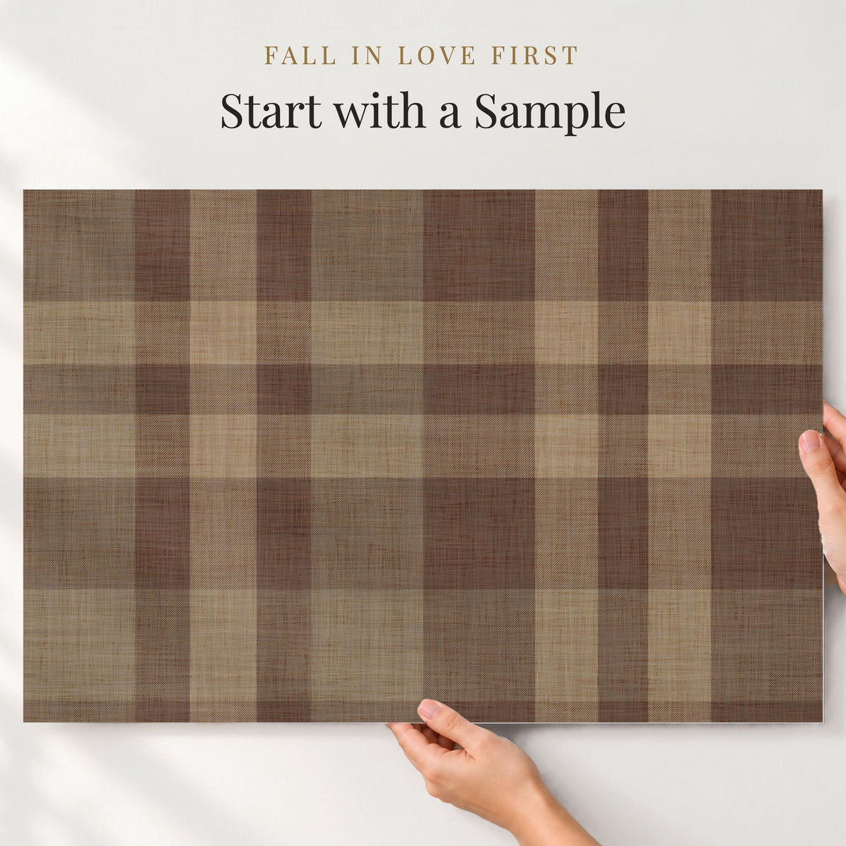 Large sample of chocolate brown plaid wallpaper held up to the wall