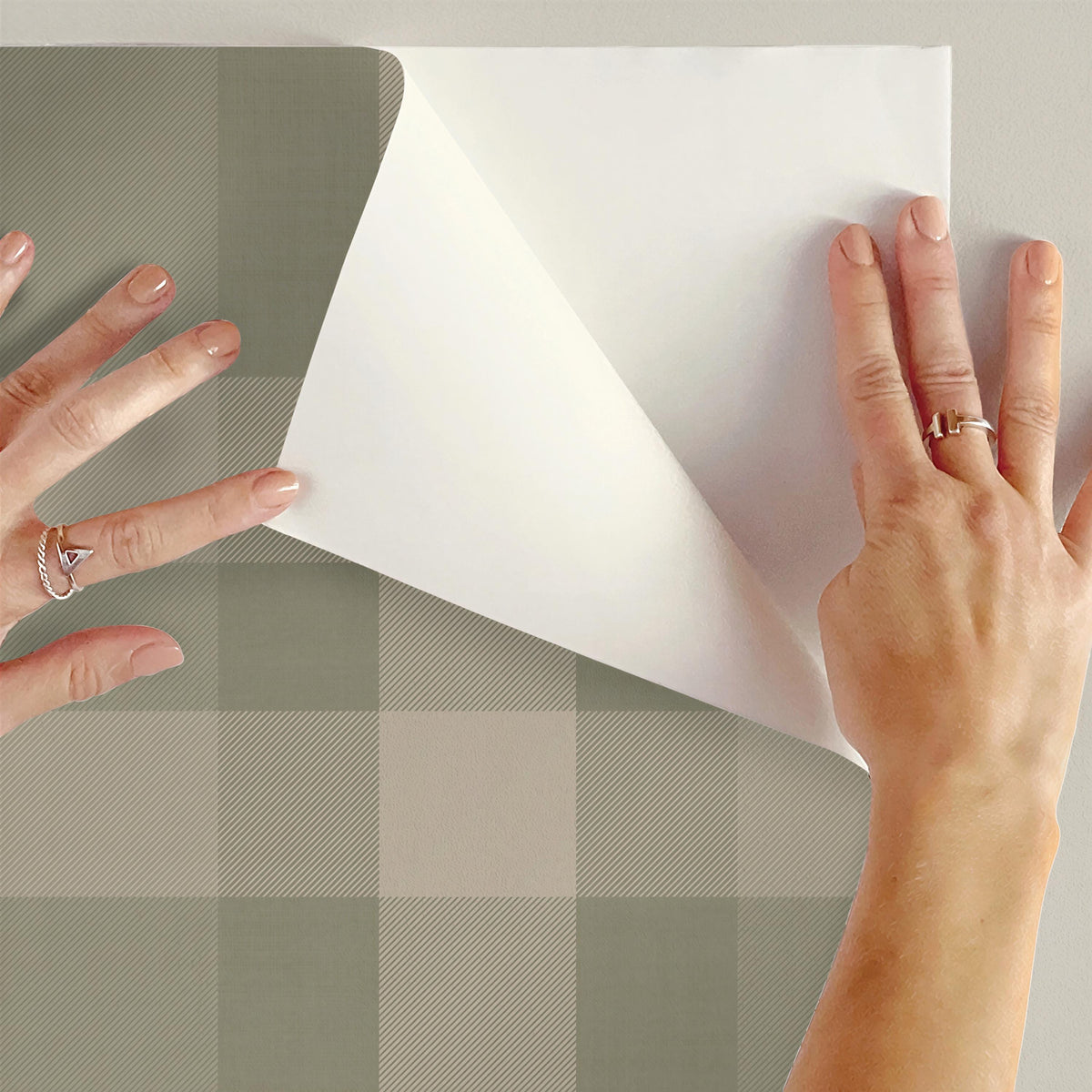 Peeling the backing off sage green plaid peel and stick wallpaper