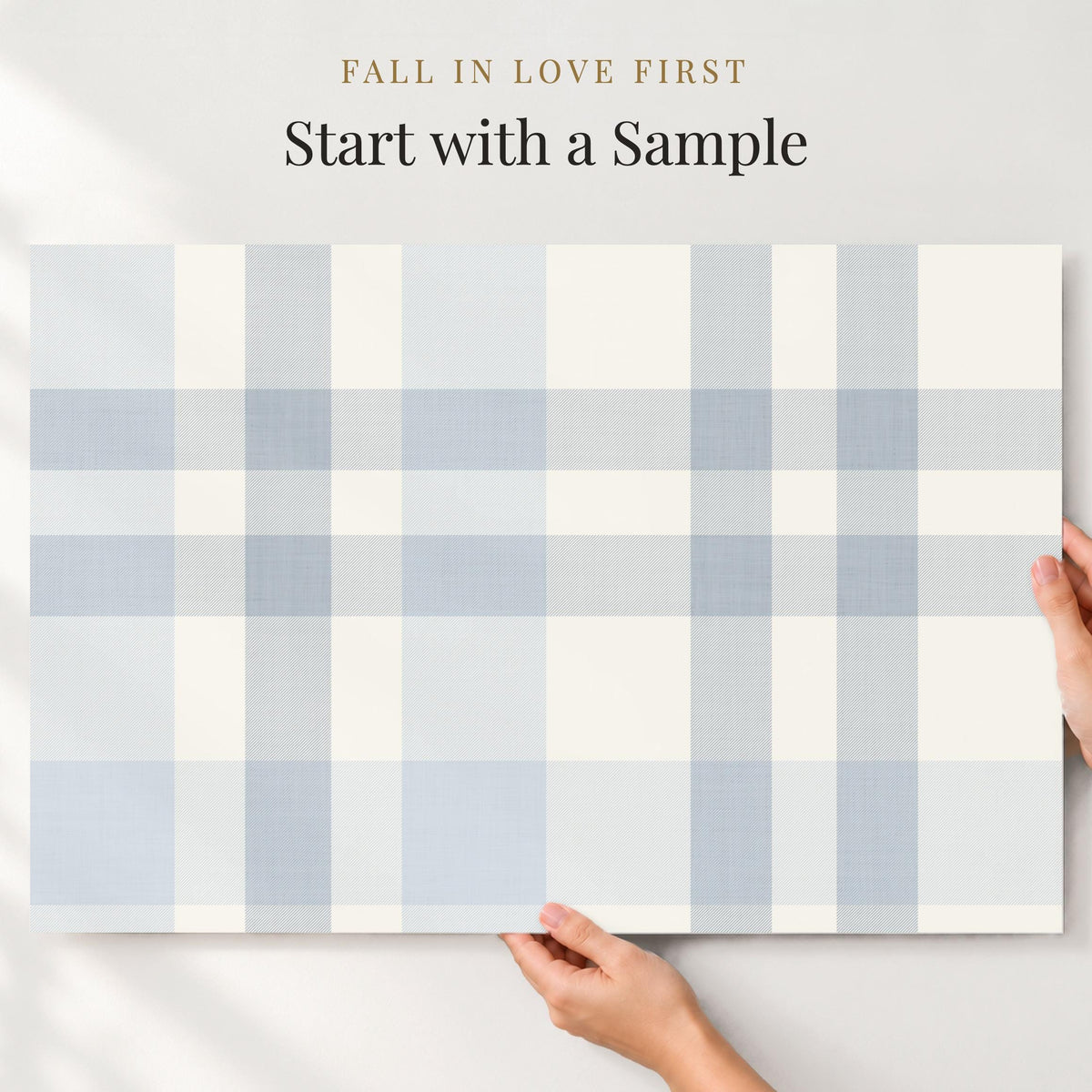 Large sample of light blue plaid wallpaper held up to the wall