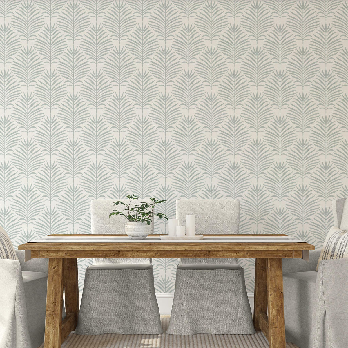 Dining room with a wood table and chairs against gray green and white Palm Breeze palm leaf wallpaper