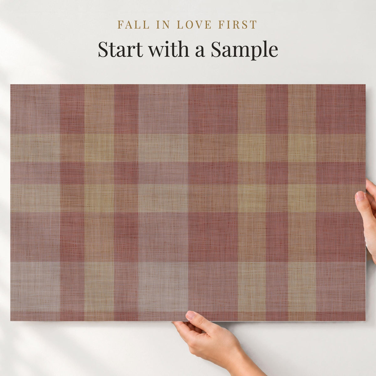 Large sample of burgundy plaid wallpaper held up to the wall