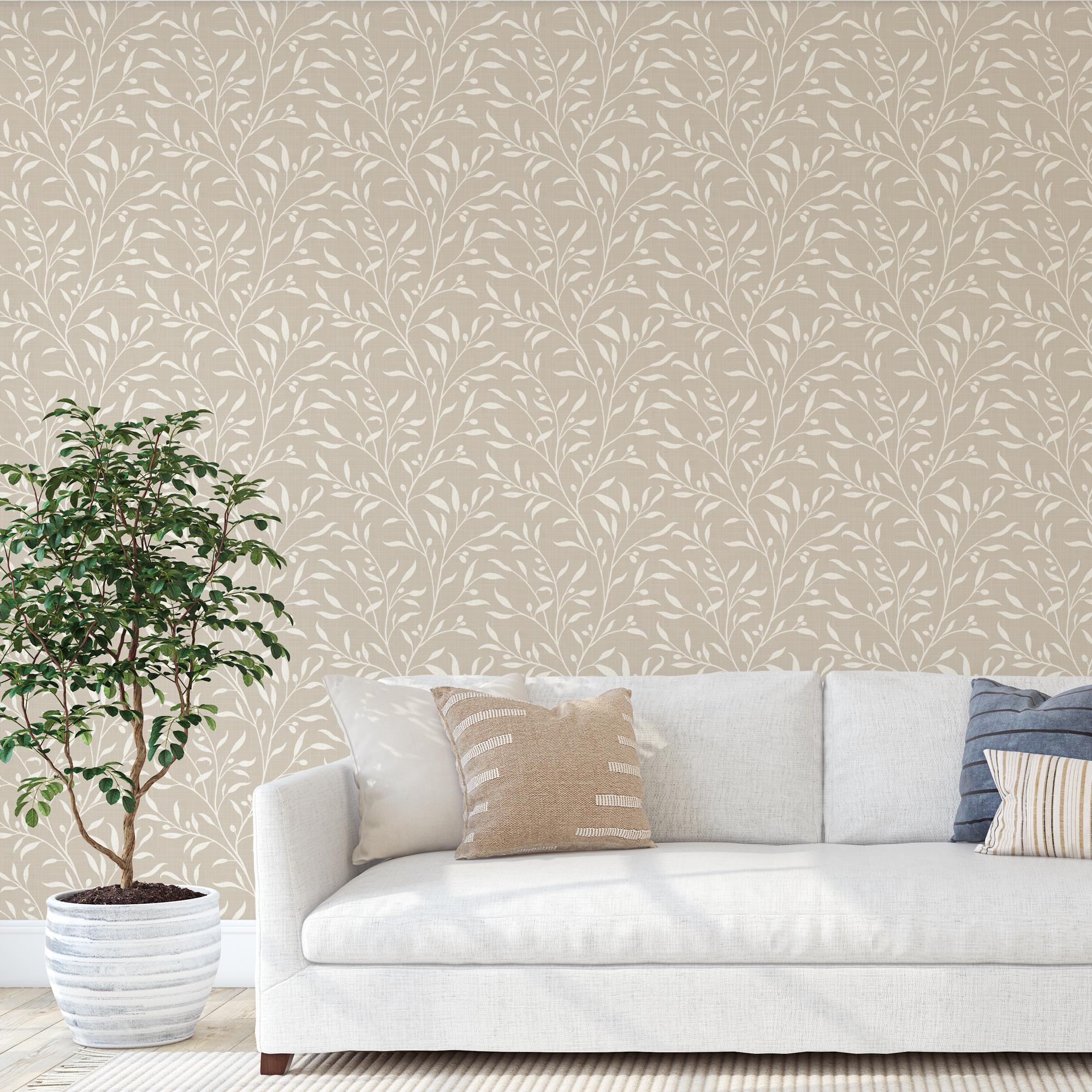 a white sofa with a plant in a white pot, set against a wall with a repeating leaf pattern wallpaper.
