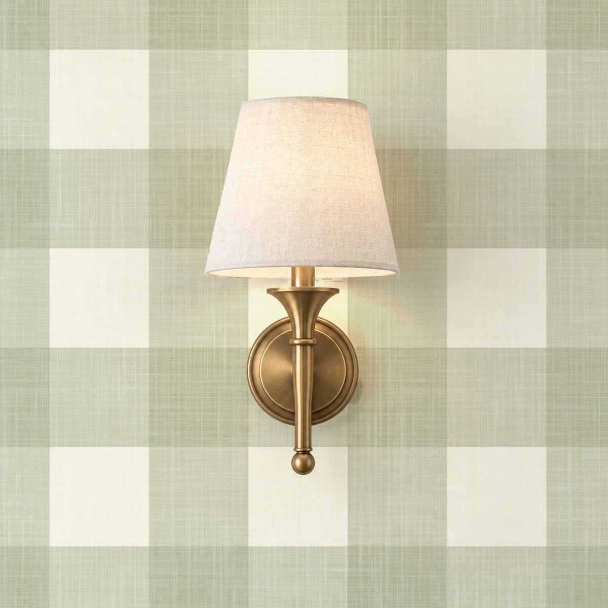 A wall-mounted light fixture with a white lamp shade is mounted on a wall with a green and white checkered pattern.