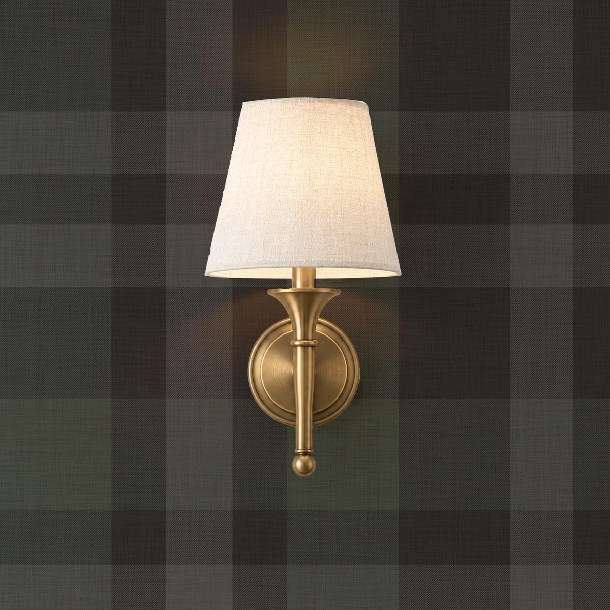 Black plaid wallpaper with a brass sconce in a moody library style room
