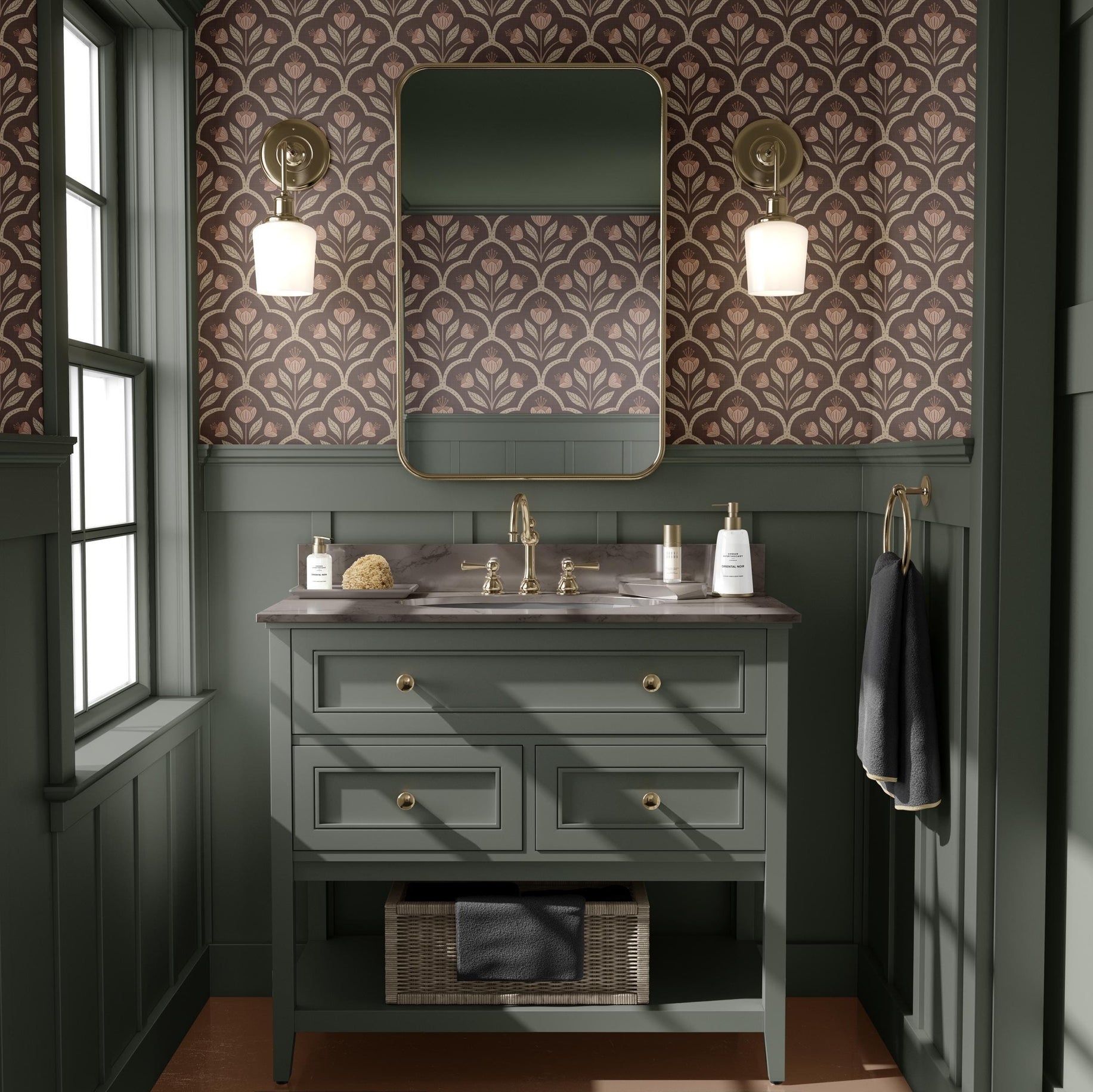 May include: A green bathroom vanity with a white countertop and a mirror above. The vanity has three drawers and a shelf below. There is a black towel hanging on a hook on the wall. The walls are covered in a pink and brown floral wallpaper.